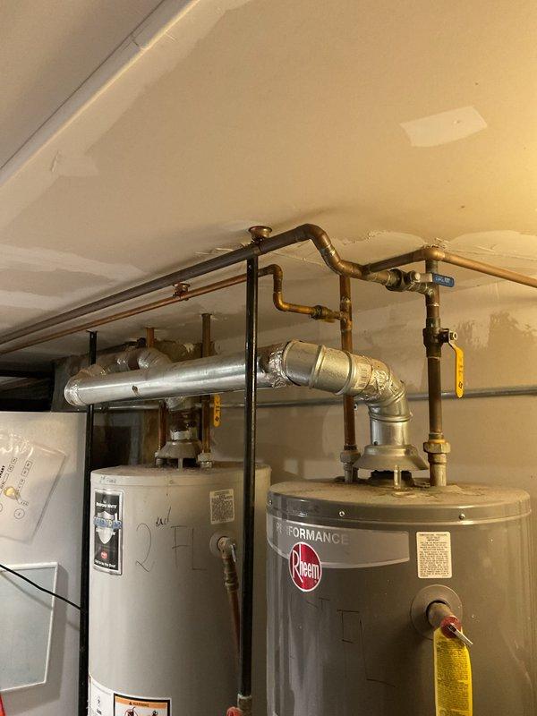 Conducted a site assessment for potential tankless water heater installation at customer's tavern. Current setup includes two conventional tank water heaters (one Rheem Performance model) with standard copper piping and metal exhaust venting. Evaluated existing utility room configuration and plumbing connections to determine feasibility of conversion to tankless system.
