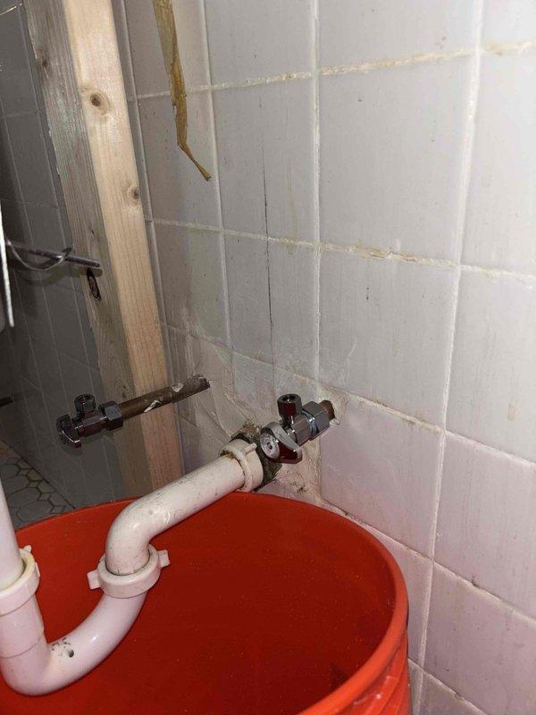 Responded to water leak service request before 2PM. Inspected copper supply lines showing discoloration and a compromised connection at the wall junction. Installed temporary PVC drainage solution with containment basin to prevent further water damage to surrounding tile and structure while awaiting permanent repair.