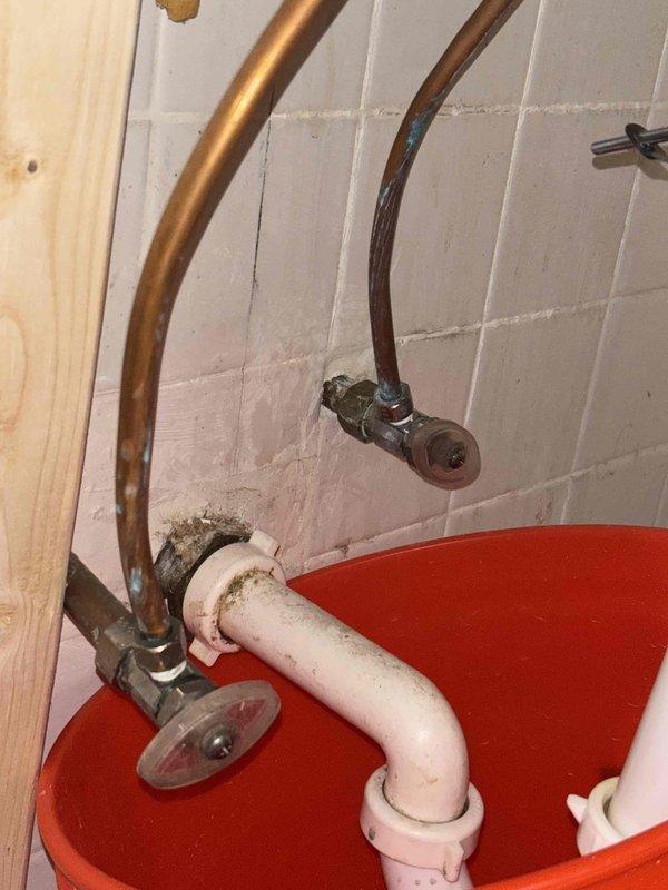 Responded to water leak service request before 2PM. Inspected copper supply lines showing discoloration and a compromised connection at the wall junction. Installed temporary PVC drainage solution with containment basin to prevent further water damage to surrounding tile and structure while awaiting permanent repair.