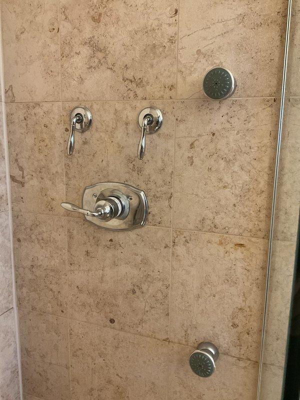 Responded to service call regarding shower temperature adjustment issues. Diagnosed and repaired thermostatic mixing valve in dual-head shower system with chrome fixtures. Verified proper water heater operation (Rheem Performance model) with all connections secure and functioning correctly.