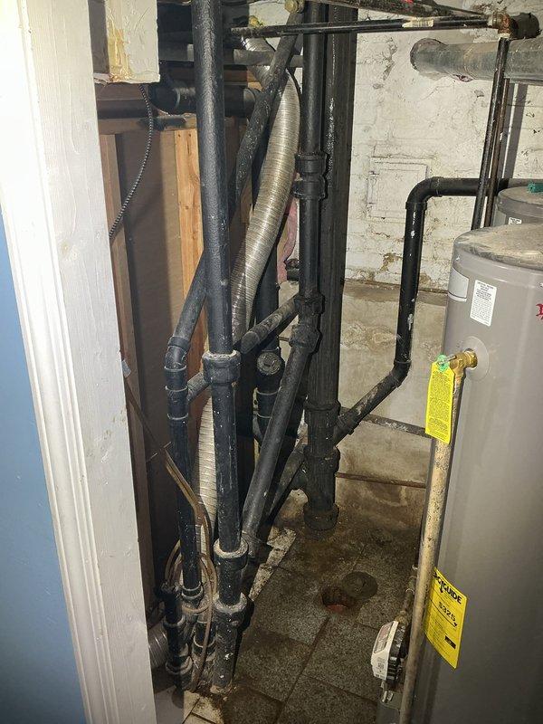 Responded to callback regarding standing water issue. Inspection revealed stagnant, contaminated water pooling in a damaged floor opening near plumbing infrastructure. Documented extensive water damage to surrounding tile and concrete, with visible staining on basement utility area walls where multiple black pipes and water heater are located.