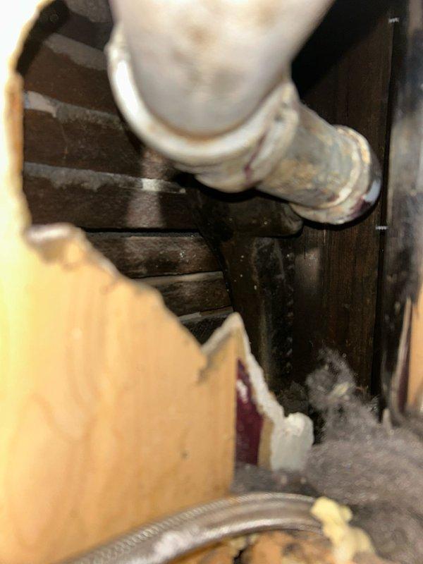 Located and identified source of water leak in basement, which was found to be originating from deteriorated connections between older metal piping and newer PVC components. Performed inspection of surrounding plumbing infrastructure including water heater system and associated piping network, documenting conditions with photographs for record.