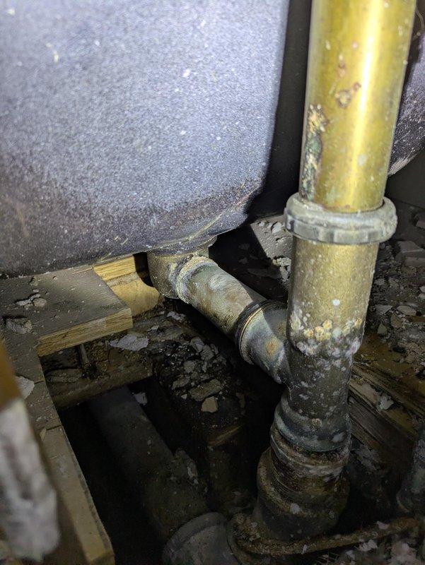 Located and diagnosed a bathtub drain leak where the slip joint nut had completely disintegrated. Observed significant corrosion and mineral deposits on brass/copper pipes, particularly at the connection point highlighted by customer. The horizontal pipe was seized in place due to extensive oxidation and could not be removed without replacement.