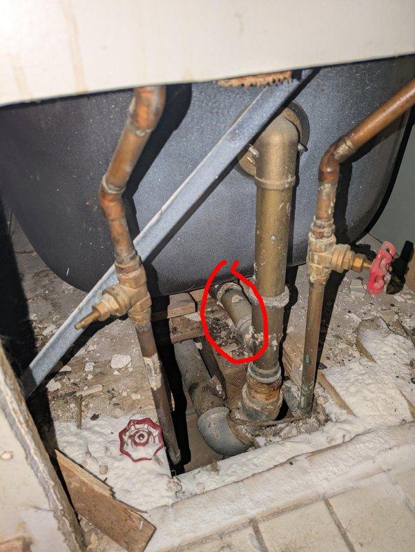 Located and diagnosed a bathtub drain leak where the slip joint nut had completely disintegrated. Observed significant corrosion and mineral deposits on brass/copper pipes, particularly at the connection point highlighted by customer. The horizontal pipe was seized in place due to extensive oxidation and could not be removed without replacement.
