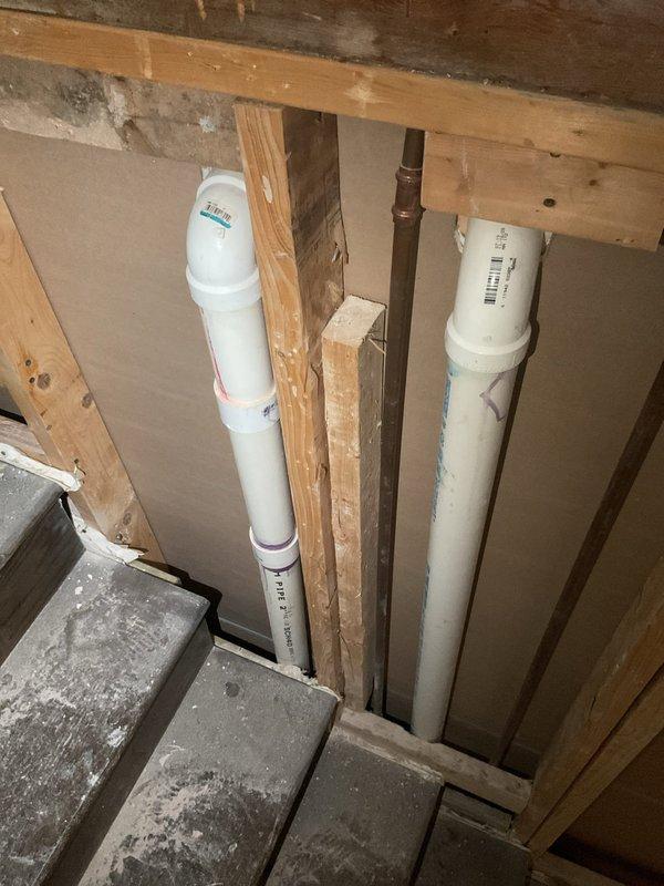 Conducted comprehensive inspection of residential plumbing system in preparation for installing two kitchen sinks and three bathroom sinks. Examined existing PVC and metal piping infrastructure in utility area, noting proper structural support within wooden framing. Evaluated unfinished bathroom/kitchen space with exposed wall-mounted and ceiling-mounted PVC supply lines, confirming readiness for fixture installation once drywall completion is finalized.