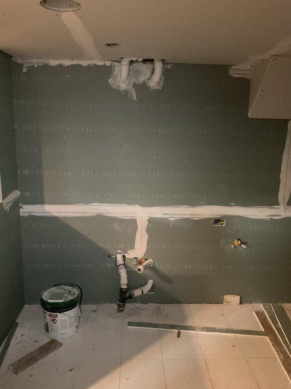 Conducted comprehensive inspection of residential plumbing system in preparation for installing two kitchen sinks and three bathroom sinks. Examined existing PVC and metal piping infrastructure in utility area, noting proper structural support within wooden framing. Evaluated unfinished bathroom/kitchen space with exposed wall-mounted and ceiling-mounted PVC supply lines, confirming readiness for fixture installation once drywall completion is finalized.