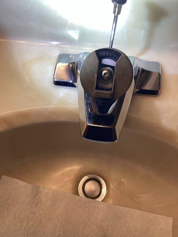 Inspected Moen bathroom sink faucet and discovered the screw holding the handle mechanism is stripped and unable to be removed without damaging internal gears. Removal would require cutting, which would compromise the fixture's functionality. Customer will obtain a replacement faucet from manufacturer and schedule a follow-up installation service.
