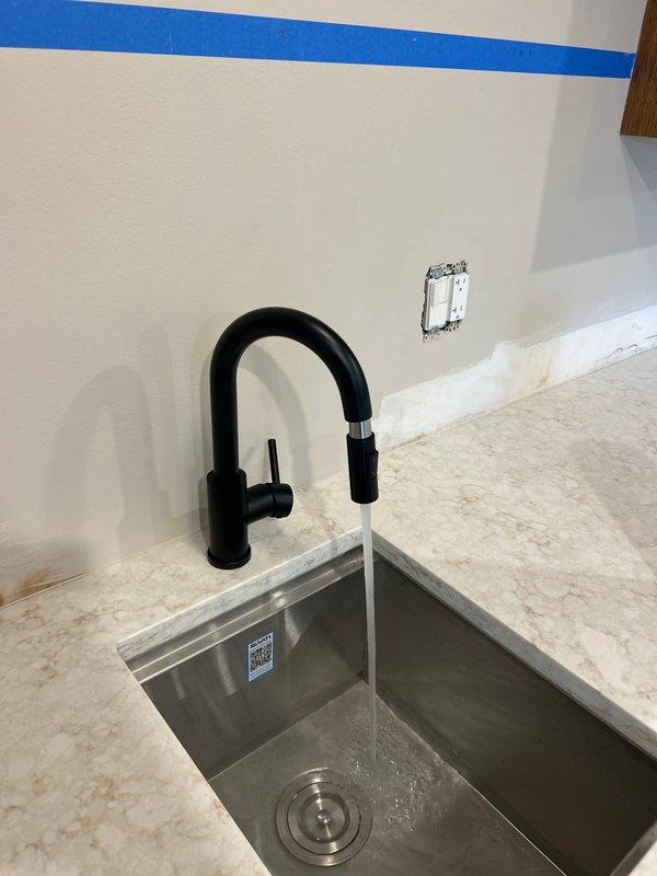 Successfully installed a 15" Ruvati undermount sink and gooseneck faucet for wet bar, connecting all necessary plumbing components including P-trap assembly and supply lines. Completed final testing with water flow to verify proper drainage and absence of leaks in the new installation.