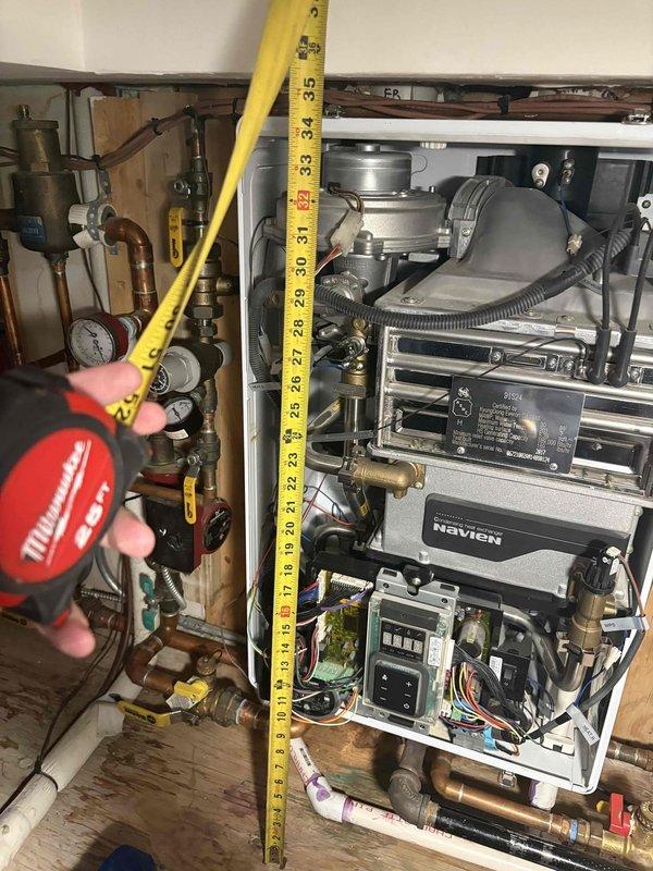 Diagnosed Navien tankless water heater system experiencing operational issues. Conducted comprehensive inspection of unit with front panel removed, examining internal components including control board, valves, and electrical connections. Took measurements of system configuration to evaluate proper installation parameters and determine appropriate repair or replacement options.