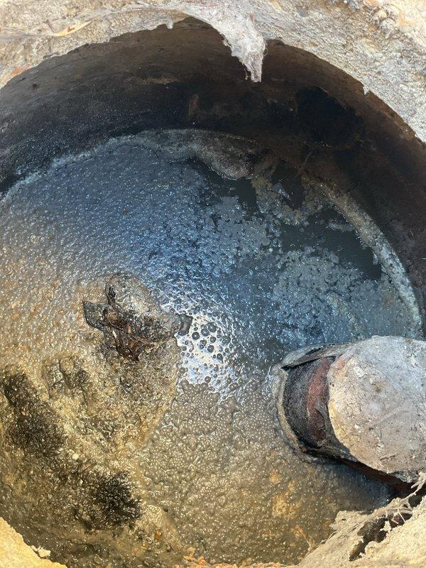 Performed inspection of commercial grease trap system and associated sewer line as requested. Observed significant deterioration and cracking around access point, standing water with visible debris, and signs of rust/corrosion at pipe connections. Backup power system with dual batteries appears to be functioning normally with proper connections and secure mounting.