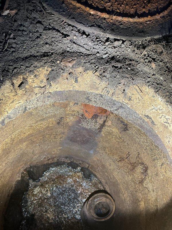 Performed callback inspection of downspout drainage system. Documented significant mineral buildup and corrosion in the circular drainage component, with extensive deterioration visible in the connecting pipe structure. Photographed evidence of standing water and sediment accumulation for estimate preparation to completely re-pipe downspout line to catch basin.