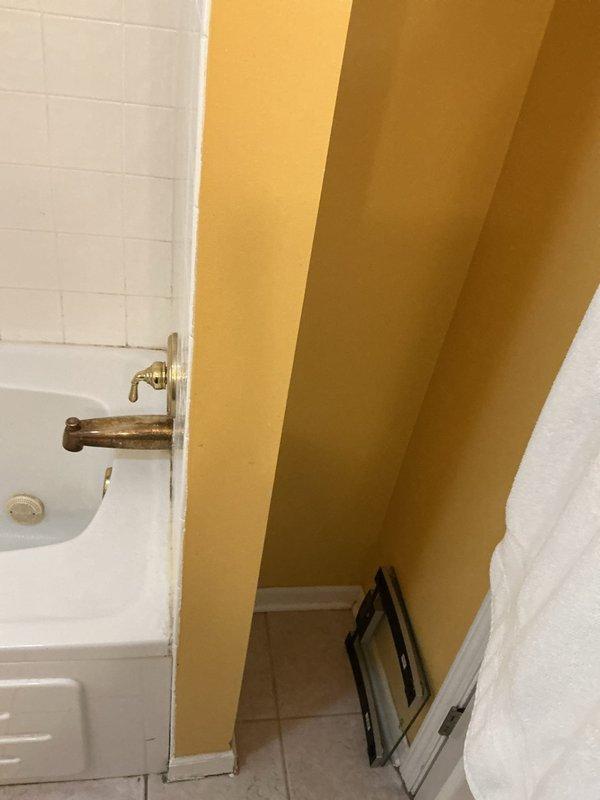 Performed diagnostic inspection of bathroom to locate reported water leak. Inspected shower/tub installation, including brass fixtures, valve assembly, and drain connections. Assessed toilet for potential leakage and examined drainage system in bathtub that required rodding. Documented existing conditions with photographs showing aged brass fixtures and possible areas of water intrusion around tile grout and tub perimeter.