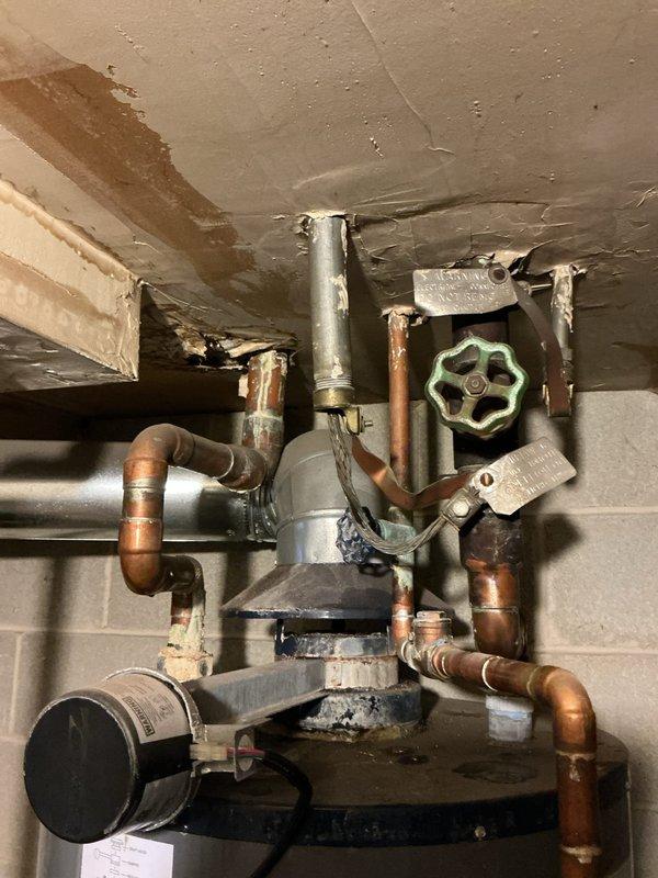 Conducted assessment of leaking water heater installation in basement utility room. Observed Bock brand unit with extensive copper piping system showing signs of corrosion and visible ceiling water damage near pipe connections. Estimate provided for complete replacement of existing water heater to address active leak and prevent further structural damage.