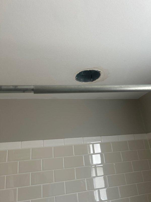 Responded to a reported ceiling leak in bathroom where water was dripping from a light fixture. Inspection revealed the source originated from plumbing in the ceiling of the bathroom above. Created access openings in the ceiling to expose the plumbing components, identifying brass pipes and connections requiring repair. Located and addressed the leak source to prevent further water damage.