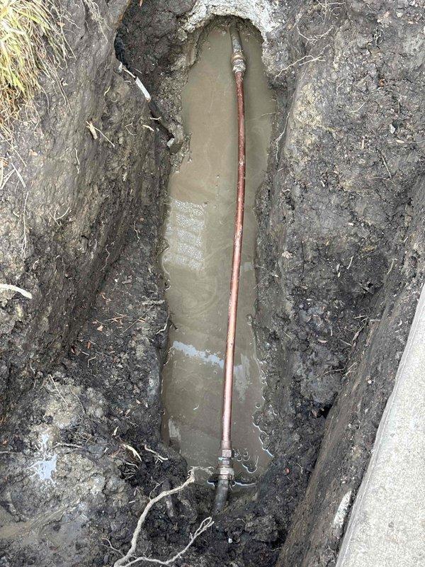 Excavated trench to access and repair damaged copper water supply line that was causing complete water service interruption. Removed accumulated groundwater from excavation site and replaced compromised pipe section with new copper piping and appropriate fittings. Service restored water flow to residence where small children were present.