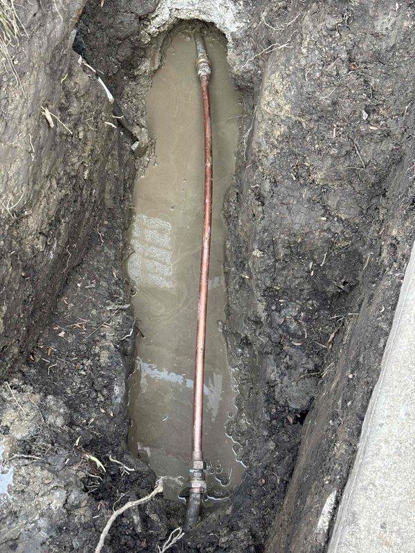 Excavated trench to access and repair damaged copper water supply line that was causing complete water service interruption. Removed accumulated groundwater from excavation site and replaced compromised pipe section with new copper piping and appropriate fittings. Service restored water flow to residence where small children were present.