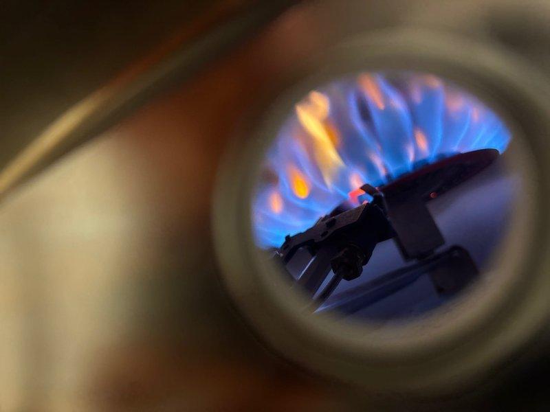 Responded to service call for water heater producing only warm water. Performed diagnostic inspection on gas tanked water heater system, which included examination of burner assembly showing proper blue flame pattern with minimal yellow tips indicating good combustion. Verified expansion tank and copper plumbing connections were intact and functioning properly.