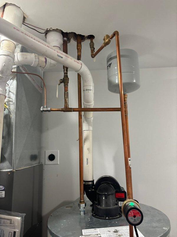 Responded to service call for water heater producing only warm water. Performed diagnostic inspection on gas tanked water heater system, which included examination of burner assembly showing proper blue flame pattern with minimal yellow tips indicating good combustion. Verified expansion tank and copper plumbing connections were intact and functioning properly.