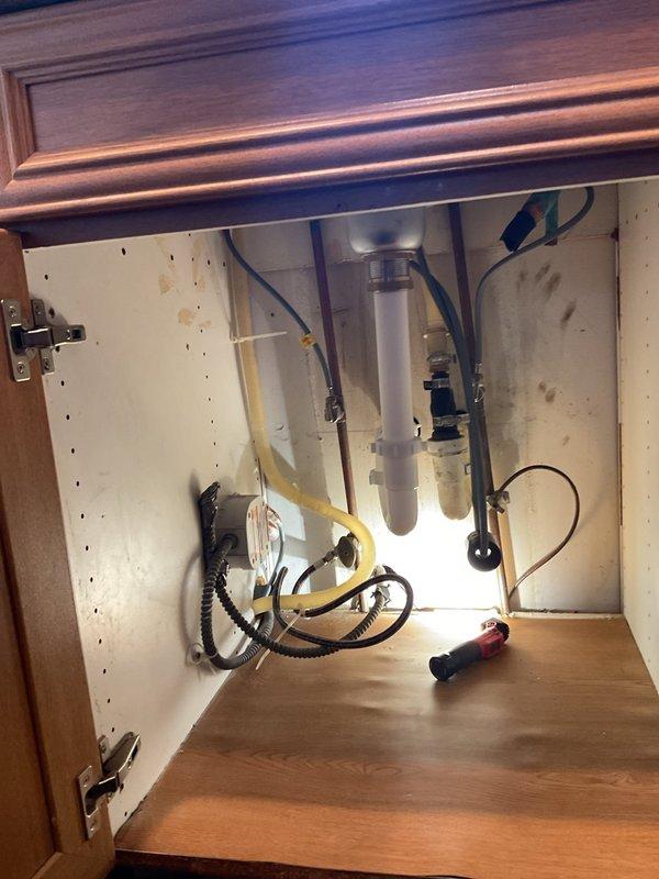 Removed existing garbage disposal from under-sink cabinet as requested. Documented the plumbing configuration which included PVC drain pipes, flexible hoses, and associated connections. Inspected adjacent utility area containing copper and PVC piping to ensure proper system integration.