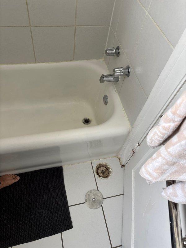 Located and investigated water leak originating from Unit 2W affecting Unit 1W. Accessed plumbing through wall panel to inspect pipe connections and identified source of leak. Visual inspection of bathroom revealed signs of seepage around bathtub drain area requiring attention to prevent further water damage to lower unit.