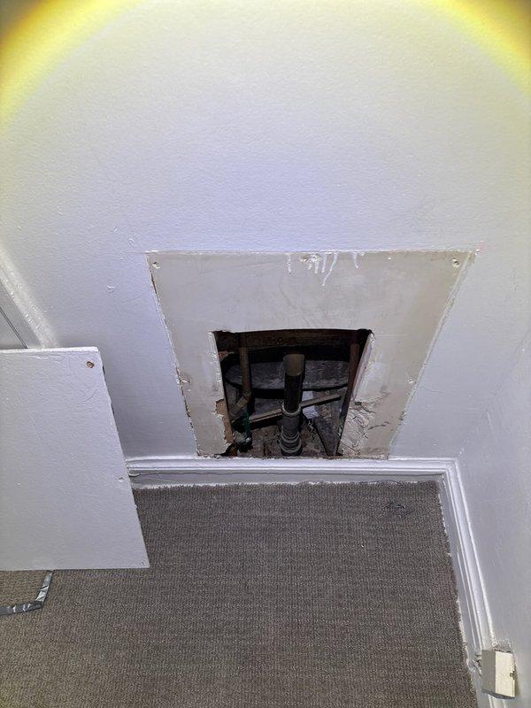Located and investigated water leak originating from Unit 2W affecting Unit 1W. Accessed plumbing through wall panel to inspect pipe connections and identified source of leak. Visual inspection of bathroom revealed signs of seepage around bathtub drain area requiring attention to prevent further water damage to lower unit.