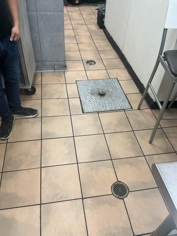 Responded to commercial kitchen drainage issue requiring assessment for hydrojetting service. Inspected two floor drains in food service area showing signs of clogging. Evaluated external drainage access point and set up safety cones to prepare for potential service area.