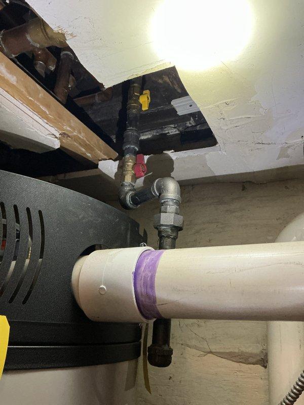 Responded to no hot water complaint at 10-unit condo building with approximately 4-5 year old water heater. Upon inspection, discovered significant ceiling damage indicating water leakage from plumbing system. Identified compromised PVC piping with purple primer marks and examined gas valve connections to diagnose and resolve the hot water supply issue.