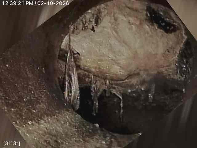 Conducted inspection of main line using camera equipment, revealing significant mineral deposits forming stalactite-like structures and extensive ice buildup within the pipe. Documentation shows severe internal damage at approximately 31' and 47' points in the line, indicating potential water infiltration and freezing issues that will require excavation and replacement of damaged sections.