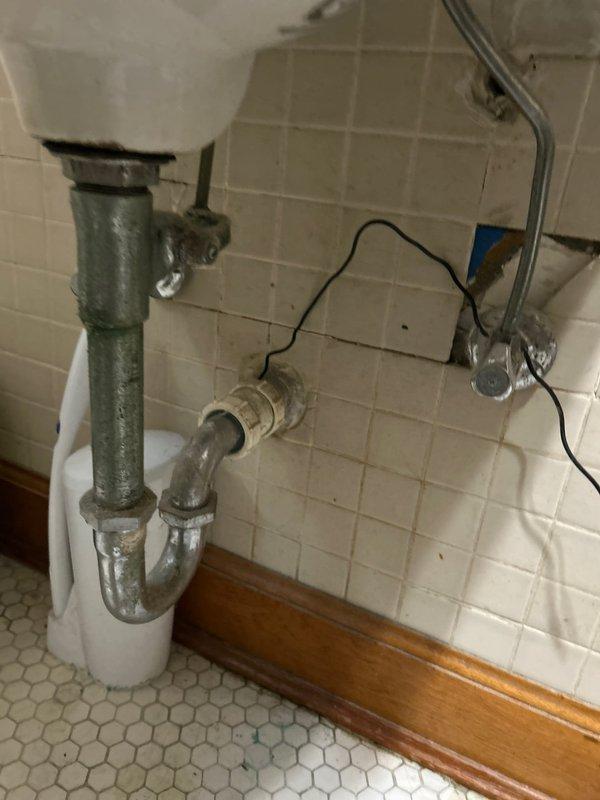 Identified and repaired significant water leak in bathroom sink plumbing that was affecting unit below. Inspection revealed heavily corroded galvanized P-trap assembly with failing connection points, particularly at the T-joint where severe rust had compromised the seal. Replaced damaged sections with new fittings, verified proper drainage, and confirmed leak resolution with access to the affected unit below.