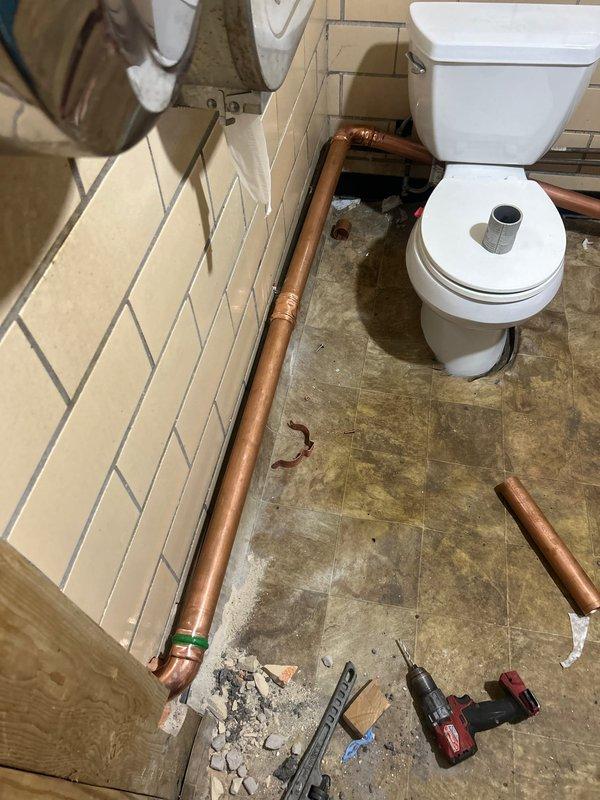 Installed copper piping for RPZ drain system in basement utility area, including necessary brass valves and fittings. Extended copper supply lines through bathroom, completing connections to existing plumbing infrastructure while maintaining proper support and alignment of all components.