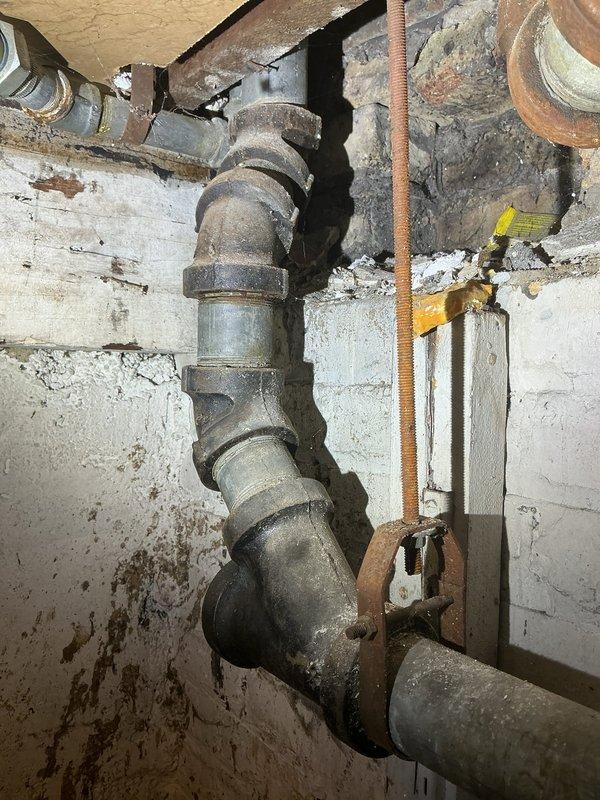 Conducted basement inspection to provide estimate for complete piping replacement. Identified severely corroded metal pipes with significant deterioration including visible holes, advanced rust, and water damage to surrounding concrete walls. Documented extensive pipe system degradation requiring full replacement due to age and moisture exposure.