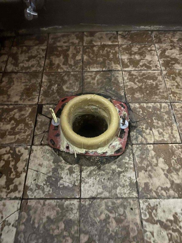 Responded to morning service call for toilet leaking at base. Upon inspection, found deteriorated toilet flange with water damage to surrounding floor tiles and mineral deposits. Removed toilet, replaced damaged wax ring and flange assembly, then reinstalled toilet with proper sealing to prevent further leakage.