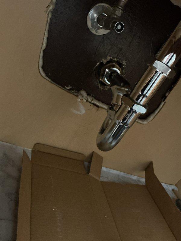 Repaired water leak under sink by replacing damaged P-trap assembly and drain connections. Installed new chrome P-trap with proper fittings and sealed pipe penetration in wall with caulking. Verified system integrity with no leaks after installation.