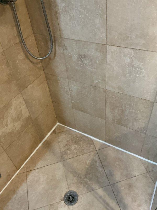 Responded to ongoing water leak investigation where previous mitigation company had removed flooring that was not drying properly. Conducted thorough inspection of bathroom shower area, examining the tiled enclosure, drain system, and waterproofing seals for potential leakage points. Identified and documented water spots and mineral deposits on wall surfaces that may indicate source of persistent moisture issue.