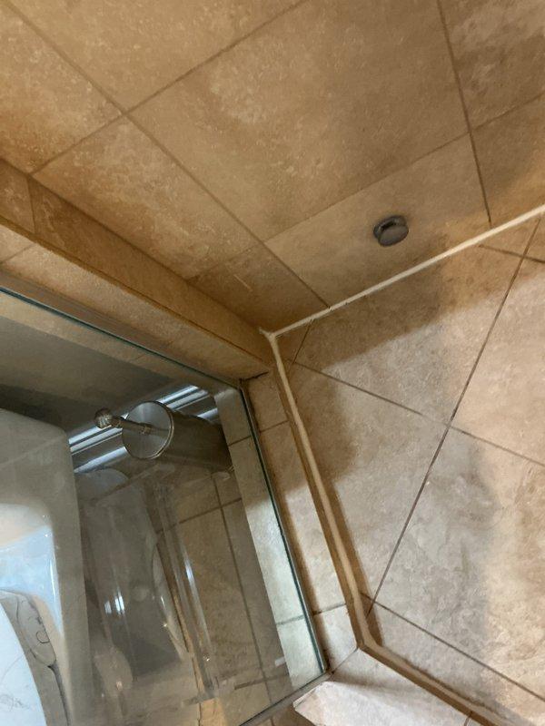 Responded to ongoing water leak investigation where previous mitigation company had removed flooring that was not drying properly. Conducted thorough inspection of bathroom shower area, examining the tiled enclosure, drain system, and waterproofing seals for potential leakage points. Identified and documented water spots and mineral deposits on wall surfaces that may indicate source of persistent moisture issue.