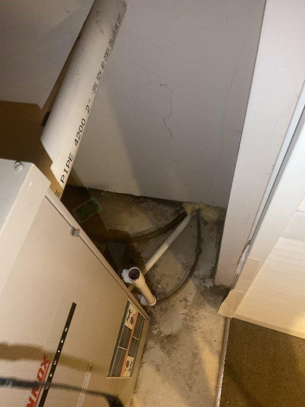 Inspected leaking tanked water heater in basement which showed visible cracking and water damage to surrounding concrete floor. Documented the existing installation including copper piping connections and gas valve assembly. Recommended complete replacement of the failed unit due to structural compromise and active leakage.