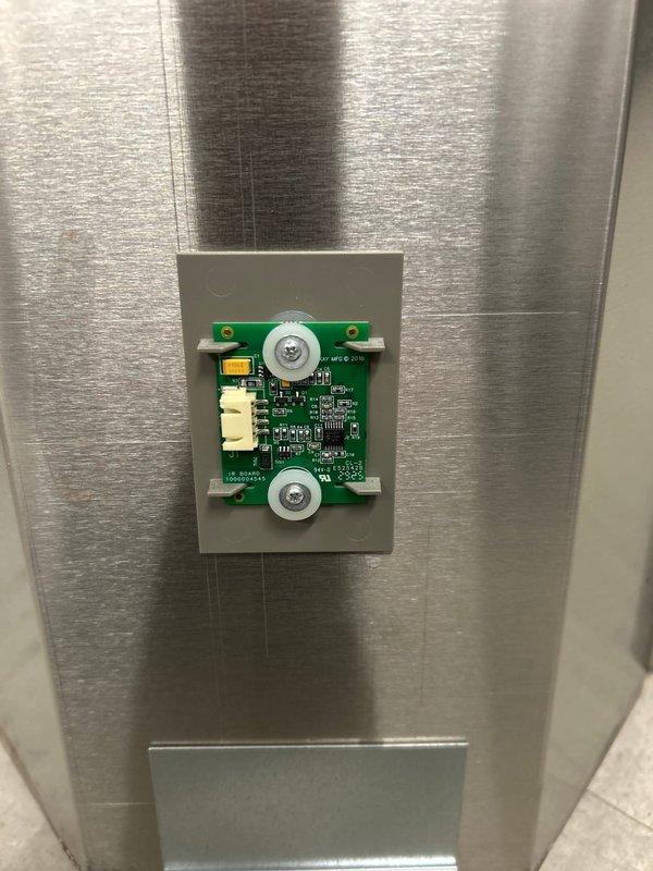 Replaced defective control board on Elkay water bottle filling station as per sold repair. Installed new circuit board in the control module housing, secured to stainless steel panel with mounting screws, and reconnected wiring harness. Unit now functioning properly with display showing correct bottle count and dispensing system operational.