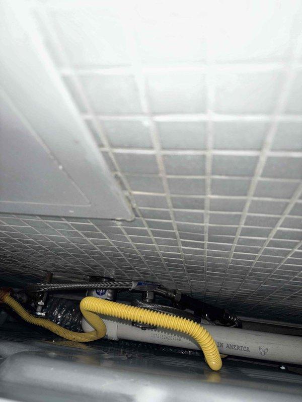 Inspected tanked water heater system and identified faulty check valve in left tankless unit. Documented existing plumbing connections and infrastructure, including PVC piping and flexible braided hoses. Will return to complete repair once warranty replacement check valve is received.