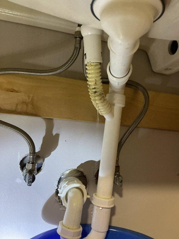 Responded to morning service call for bathroom sink leak. Upon inspection, identified a deteriorated corrugated flexible drain pipe showing significant yellowing and wear. Replaced the aging drain assembly with new PVC components and confirmed proper drainage with no further leakage.