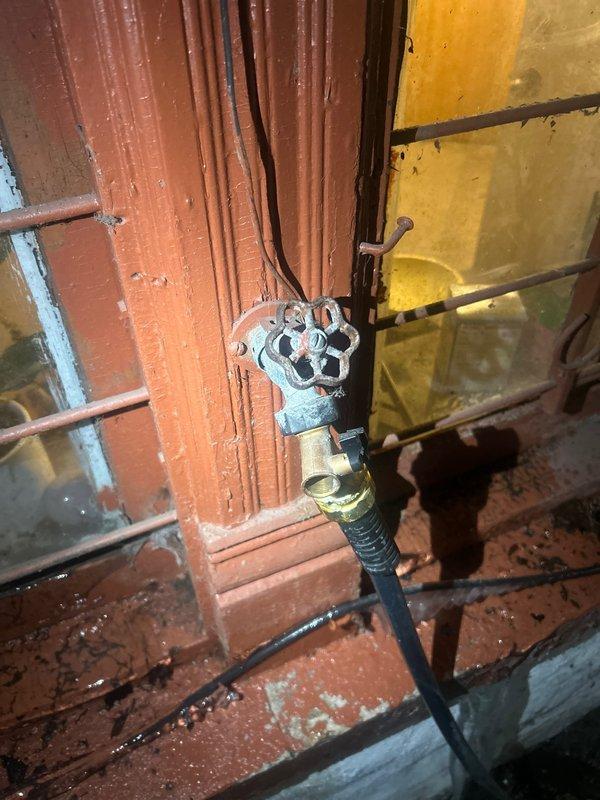 Inspected outdoor hose spigot on third-floor condo unit that had previously leaked/burst during winter. Identified corrosion on the decorative wheel handle valve and water damage to surrounding structure. Replaced damaged section of pipe, installed new frost-proof hose bibb with vacuum breaker to prevent future freezing issues, and secured all connections to restore proper functionality.