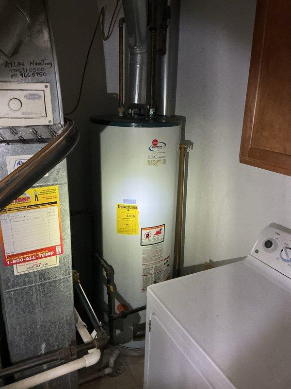 Inspected 16-year-old water heater that was leaking from the top connection points. Documented current installation in utility room with HVAC equipment and washing machine nearby. Recommended complete replacement due to age of unit and active leak.