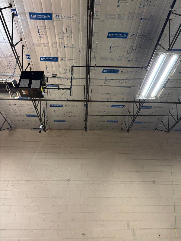 Completed installation of AP Foil-Faced insulation panels in commercial space ceiling with proper support from metal framework system. Installed and connected black piping across ceiling area, ensuring integration with existing mechanical systems. Verified operation of newly installed fluorescent lighting fixtures mounted to ceiling framework.