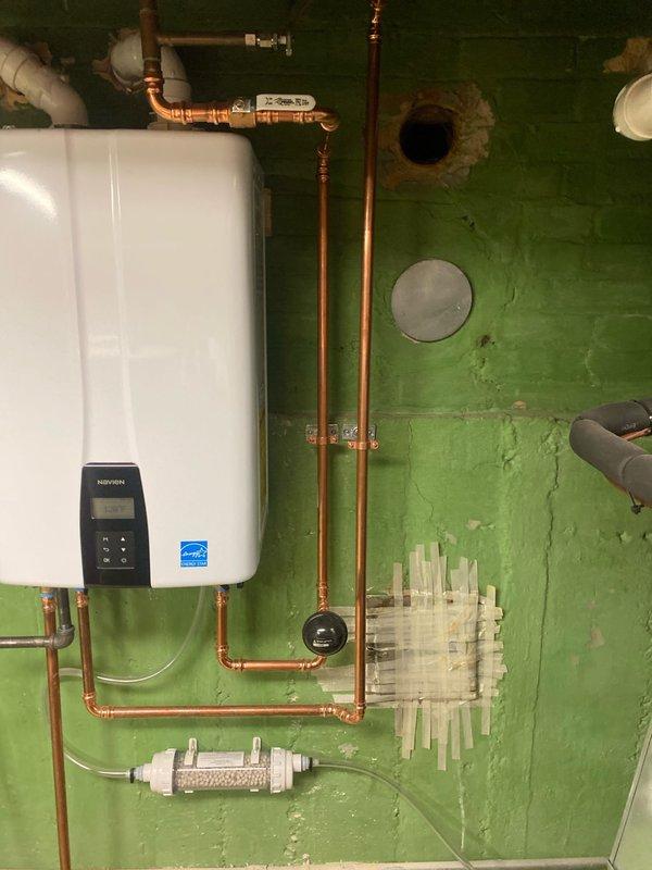 Responded to no hot water complaint. Installed new tanked water heater with Energy Star rating, complete with digital control panel and proper copper pipe connections. System includes pressure gauge and water filtration component, with all PVC drainage properly configured through existing brick wall.