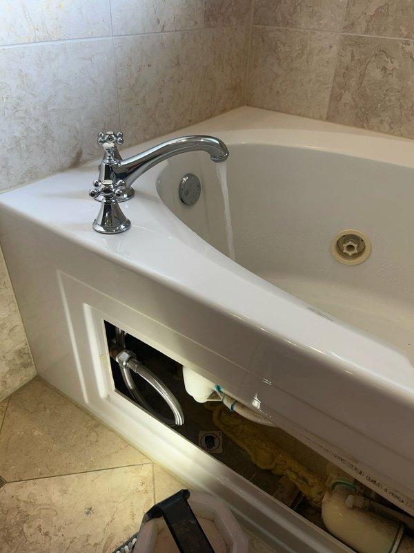 Responded to a service call regarding ceiling water leaks occurring when upstairs neighbor uses their bathtub. Conducted a thorough inspection by accessing the bathtub panel to examine plumbing connections and potential leak sources. Inspected the shower assembly including the multi-jet showerhead and flexible hose connection, identifying this as the source of water infiltration to the unit below.