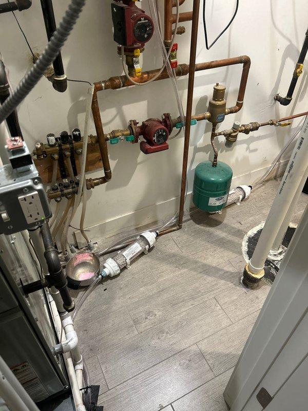 Performed inspection of existing condensate neutralizer system in mechanical room. Documented current setup including a clear cylindrical neutralizer containing white media, copper piping network with two circulation pumps, and associated valves and fittings. Prepared estimate for replacement of condensate neutralizer units to ensure proper pH treatment of acidic condensate before discharge.