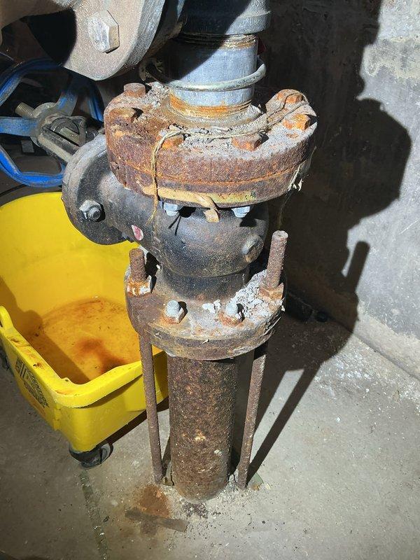 Completed inspection of residential water main system, identifying a severely corroded pipe connection and valve assembly in the utility area. Documented extensive rust damage on flanged connections, with significant deterioration visible at connection points. Recommended replacement of the corroded components to address the water main leak and prevent potential system failure.