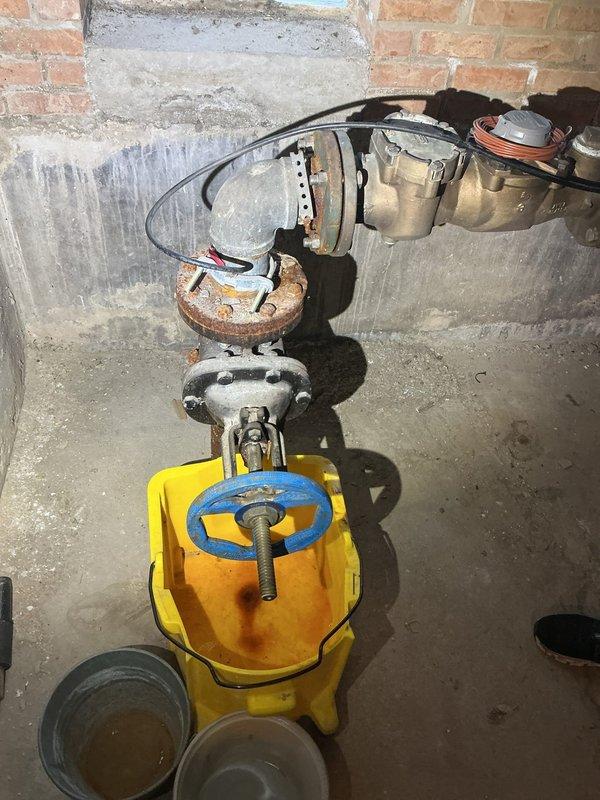 Completed inspection of residential water main system, identifying a severely corroded pipe connection and valve assembly in the utility area. Documented extensive rust damage on flanged connections, with significant deterioration visible at connection points. Recommended replacement of the corroded components to address the water main leak and prevent potential system failure.