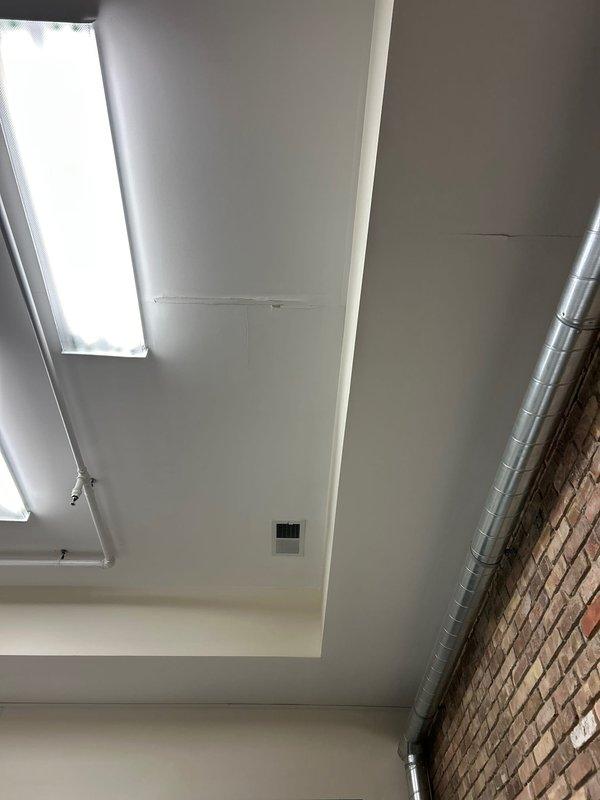 Conducted inspection of commercial ceiling area and identified significant leakage from a black metal pipe showing visible corrosion. Documented multiple streams of dark fluid dripping from the pipe surface with evidence of rust formation, potentially compromising the pipe integrity and ceiling structure. Recommended immediate replacement of affected piping sections to prevent further water damage to the surrounding OSB wall and insulation materials.