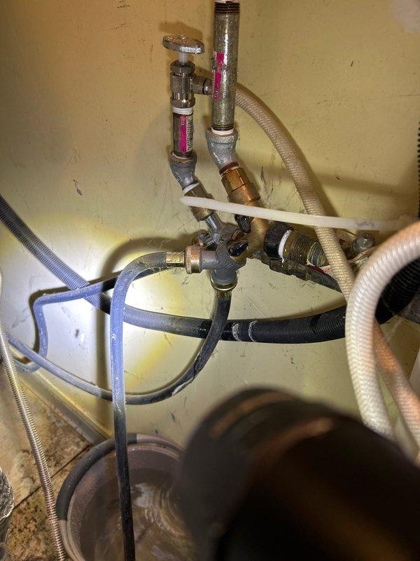 Responded to service call for leaking washing machine supply line. Upon inspection, discovered aged and corroded metal pipe connections with visible water damage on adjacent wall. Replaced the deteriorated supply hoses with new braided metal lines, properly secured all fittings, and tested system to confirm complete resolution of leak.