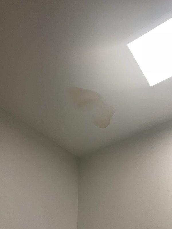Investigated water damage on ceiling beneath bathroom. Accessed wall cavity to inspect plumbing system, revealing a leaking connection between PVC main line (marked 1321-9/SKB7371) and copper branch pipes. Repaired connection, confirmed proper water flow with no further leakage, and recommended monitoring the ceiling stain for complete drying.